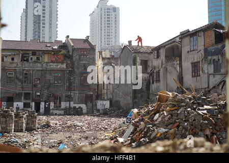 Destruction of Shanghai Longtangs. -  03/05/2016  -  China / Shanghai  -  Worker on a roof. Destruction of Shanghai Longtangs. At the beginning of the '80s, the majority of the population was living in Longtangs, that it to say small villages into cities. Ther destruction follows the growth curve, thus hectares of land await the promoter who will decide to build a Mall or a bar of buildings. Some owners are resisting and keep living in their home. Water and electricity are then cut off. The othr receive a compensation and are sent to the suburbs. Everything is recycled and used in order to bui Stock Photo