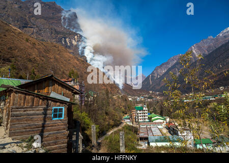 Forest fire burning on the hilly slopes in the small himalayan village town of Lachung, Sikkim India. Stock Photo