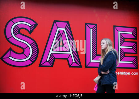 Young female shopper walks past sale sign on Oxford Street, London Stock Photo