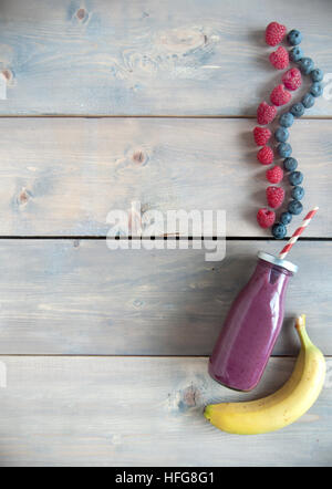 Berry flavoured smoothie in a bottle over a wooden background with copyspace Stock Photo