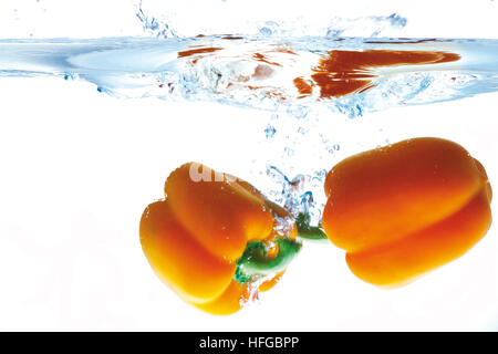Two yellow peppers dunked into water Stock Photo
