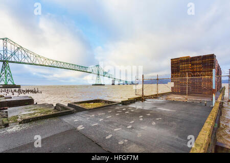 Empty pallets await cargo on dock. Astoria-Megler Bridge, Columbia River, a steel girder continuous truss bridge spanning the Columbia River between A Stock Photo