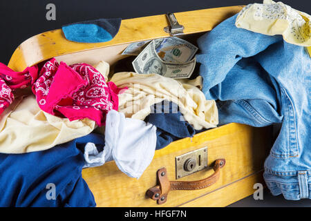 Vintage suitcase and old clothes with money. Stock Photo