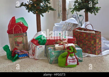 Christmas presents (including reindeer treats)  under three small christmas trees Stock Photo
