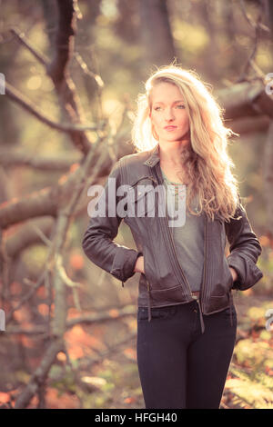 Photographic modeling as a career in the UK: A young slim attractive 20 year old caucasian woman girl with long blonde hair alone by herself in woodlands on a warm bright autumn afternoon Stock Photo