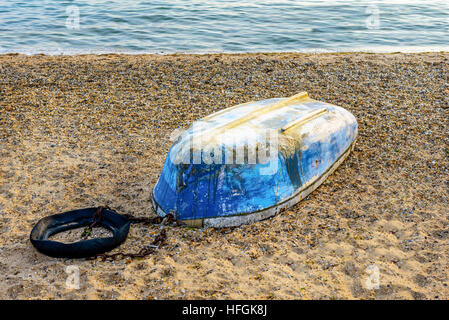 Derelict blue colored boat on a shingle beach with sea in the background. Photo taken at Shoeburyness near Southend on Sea Essex UK Stock Photo