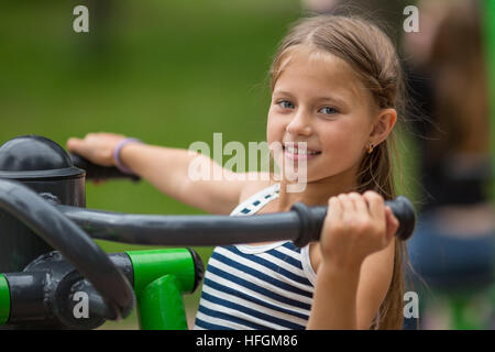 Ten-year girl doing exercises at a sports ground outdoors. Stock Photo