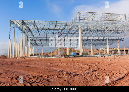 Construction Building new large warehouse factory halfway concrete pillars roofing closeup photo of structure landscape. Stock Photo