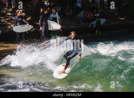 Surfer makes a turn on the artificial wave in the Eisbach in the Munich Englisher Garten, Germany. Stock Photo