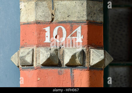 House Number 104 painted sign on wall Stock Photo