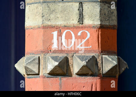 House Number 102 painted sign on wall Stock Photo