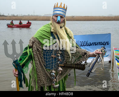 Hohenkirchen, Germany. 01st Jan, 2017. The 'Neptune God of the Sea' announces the current water temperature during the traditional New Year's swim in the lake in the Wangerland recreational area in Hohenkirchen, Germany, 01 January 2017. Over fifty participants took a swim to welcome the new year. With air and water temperatures around four degrees celsius, swimming time was kept short. Photo: Ingo Wagner/dpa/Alamy Live News Stock Photo