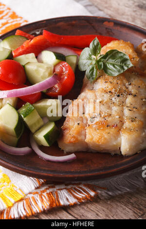 grilling fish fillets and fresh vegetable salad close-up on a plate. vertical Stock Photo