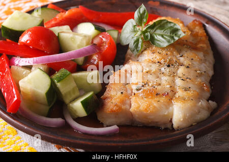 grilling fish fillets and fresh vegetable salad close-up on a plate. horizontal Stock Photo