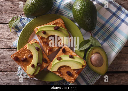 Homemade sandwiches with peanut butter, raisins and avocado close-up on a plate. horizontal top view Stock Photo