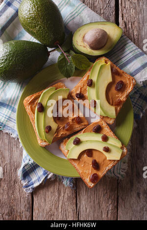 Homemade sandwiches with peanut butter, raisins and avocado close-up on a plate. vertical top view Stock Photo