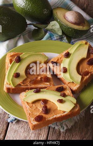 Sandwiches with peanut butter, raisins and ripe avocado close-up on a plate. Vertical Stock Photo