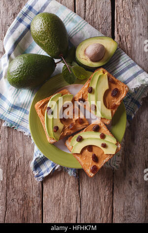 Homemade sandwiches with peanut butter, raisins and avocado on a plate. vertical top view Stock Photo