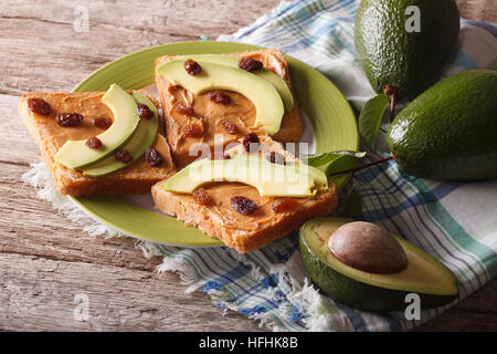 Sandwiches with peanut butter, raisins and ripe avocado close-up on a plate. horizontal Stock Photo