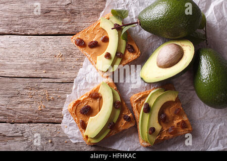 Beautiful sandwiches with avocado, peanut butter and raisins close-up on the table. horizontal view from above Stock Photo