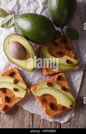 Beautiful sandwiches with avocado, peanut butter and raisins close-up on the table. vertical top view Stock Photo