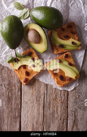 Beautiful sandwiches with avocado, peanut butter and raisins on the table. vertical top view Stock Photo