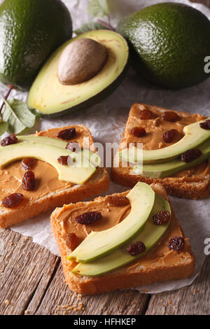 Sandwiches with avocado, peanut cream and raisins close-up on the table. vertical Stock Photo