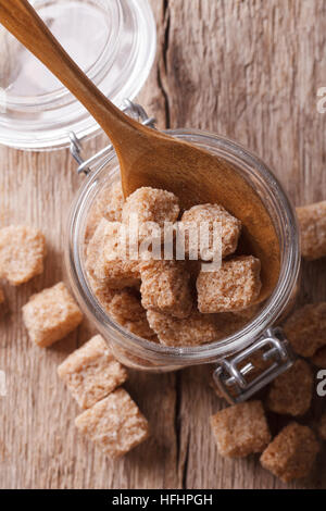 Pieces of unrefined cane sugar in a glass jar close up. vertical top view Stock Photo