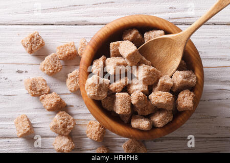 Pieces of unrefined cane sugar in a wooden bowl closeup. horizontal view from above Stock Photo