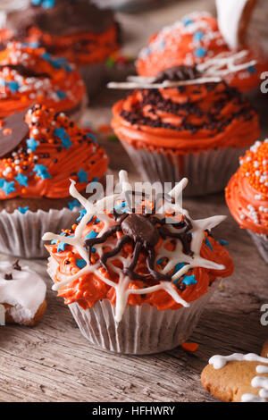 Beautiful orange Halloween cupcakes with spider close-up on the table. vertical Stock Photo