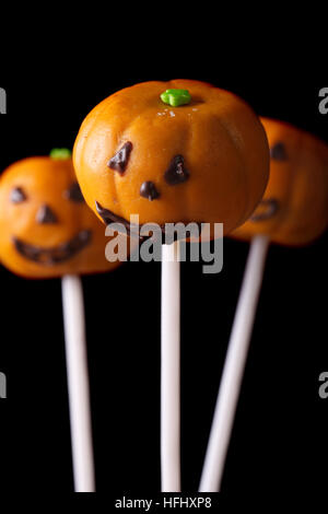 Halloween pumpkin cake pops isolated on a black background. Vertical Stock Photo