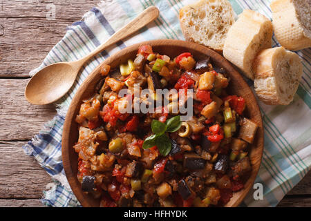 Italian Caponata with aubergines close-up in a wooden plate. horizontal view from above Stock Photo