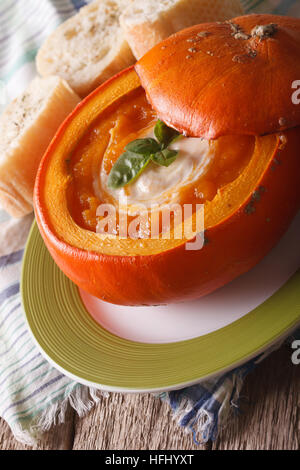 Delicious autumn soup in a pumpkin close-up on the table. vertical Stock Photo