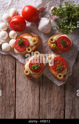 crostini with tomatoes, olives and cheese on the table. vertical top view Stock Photo