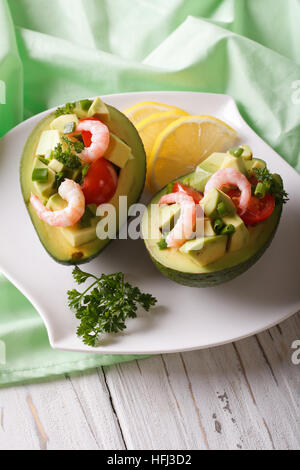 avocado filled with shrimp and vegetables on a plate close-up. Vertical Stock Photo