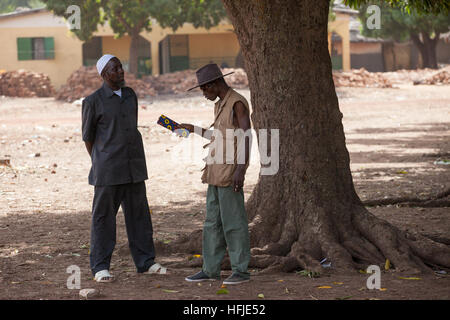 Baro village, Guinea, 1st May 2015:  Men chatting in the shade. Stock Photo