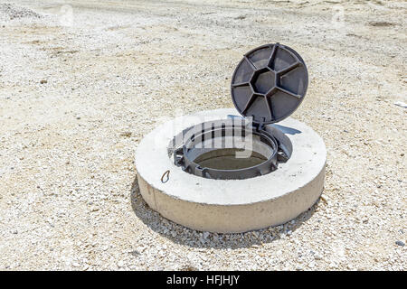 View on assembled new manhole with opened metal cover at construction site. Stock Photo