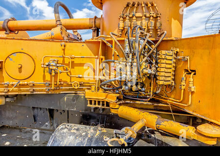 Hydraulic pressure pipes and connection fittings, levers, valves on control panel of industrial system on construction machinery. Stock Photo