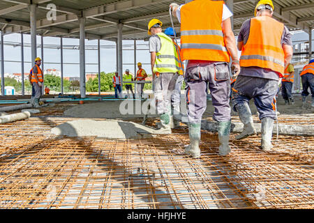 Zrenjanin, Vojvodina, Serbia - May 29, 2015: Construction workers are pouring concrete in building foundation, directing pump tube on the right direct Stock Photo