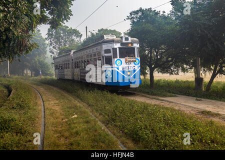 Historic Calcutta tram a mode of public transport passing through the Kolkata Maidan area on a foggy winter morning. Stock Photo