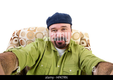 Portrait of overweight man with goatee and beret in armchair taking selfie, white background Stock Photo