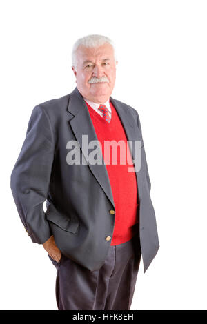 White haired senior with red sweater and suit stands with hands in his pockets Stock Photo