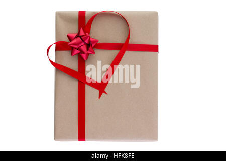 Sentimental Valentines Day gift with the red ribbon formed into a heart around a foil bow on plain brown wrapping with copy space isolated on white Stock Photo