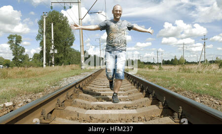 Smiling man jumping dancing on the railway tracks Stock Photo