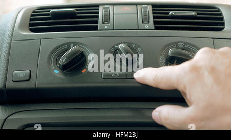 Male hand turning switch of car air conditioner Stock Photo
