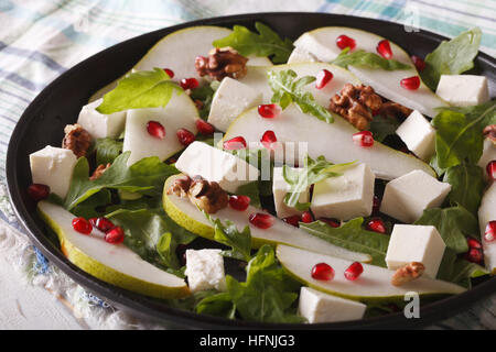 Fresh salad with pears, pomegranates, cheese, nuts and herbs close up on a plate. Horizontal Stock Photo