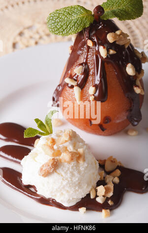 Beautiful food: Pear in chocolate with nuts and vanilla ice cream close-up on a plate. vertical Stock Photo