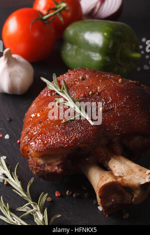 Baked pork shank and fresh vegetables closeup on the table. vertical Stock Photo