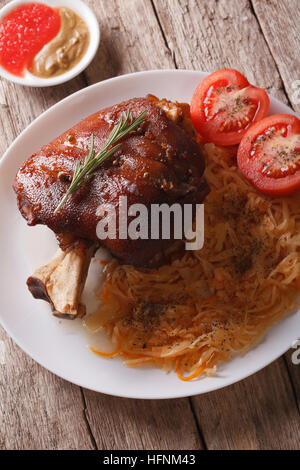 European cuisine: Baked pork knuckle and sauerkraut closeup on a plate. vertical Stock Photo