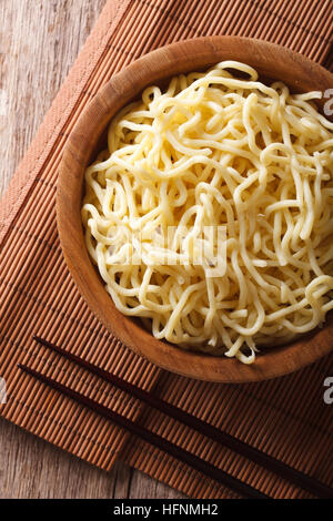 Asian ramen noodles in wooden bowl close-up on the table. vertical top view Stock Photo